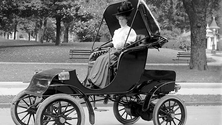 Mulher dirigindo um carro elétrico na década de 1910.