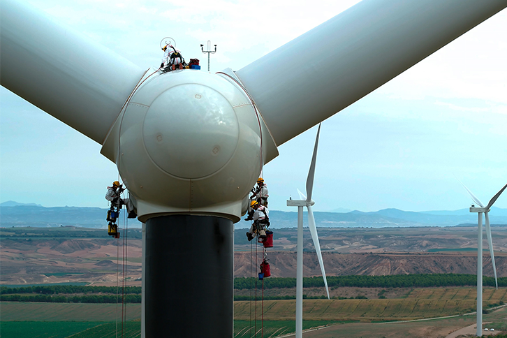 Empleados de un proveedor de Iberdrola pintando las palas de un aerogenerador en un parque eólico de la compañía.