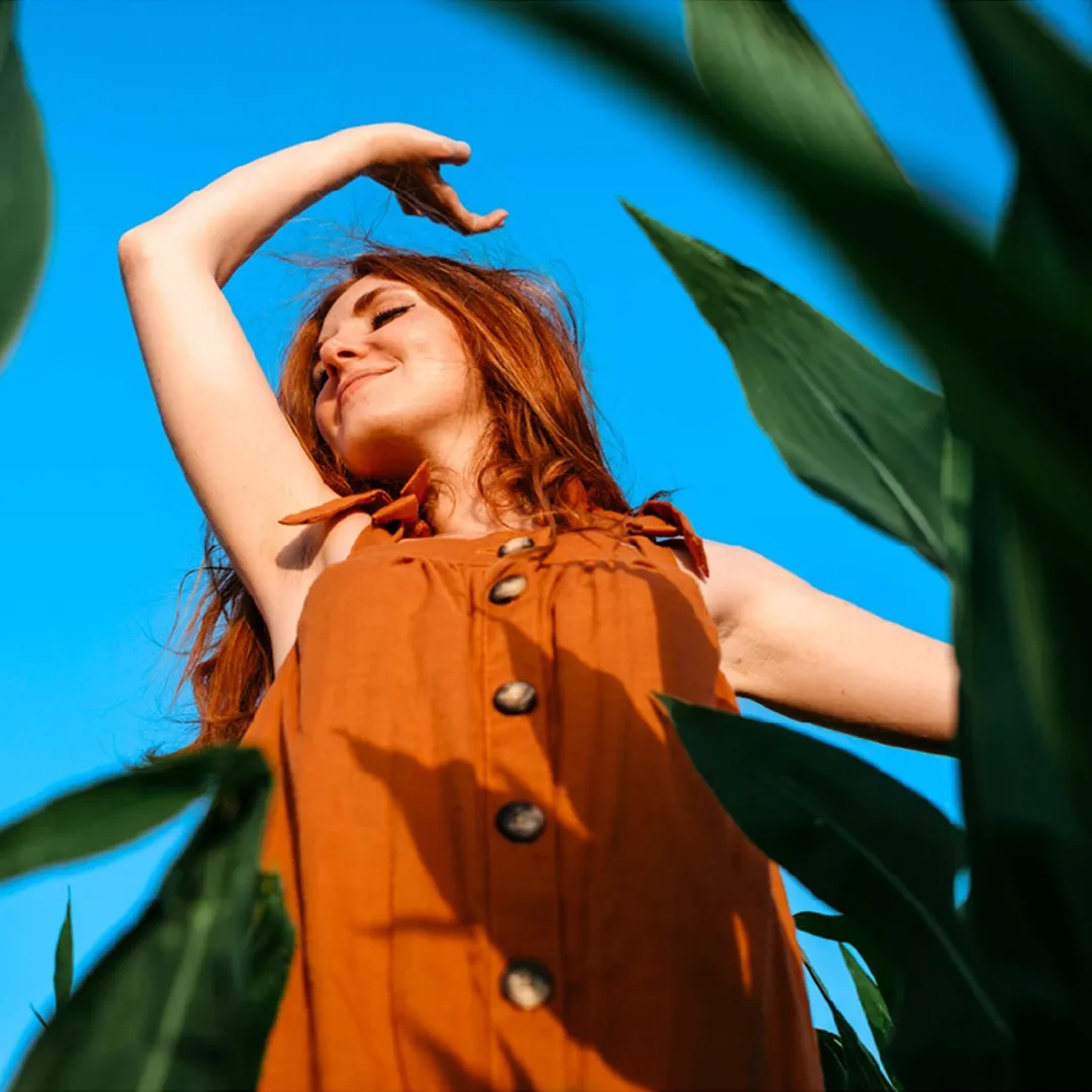 Mujer pelirroja bailando entre plantas